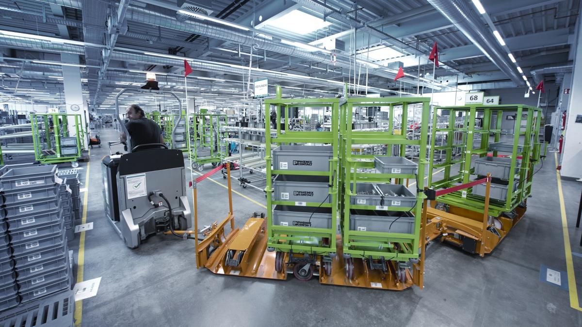 El sistema de transporte para enlazar la producción y el almacén de Phoenix Contact en Herrenberg consiste en un tren de arrastre en cada piso, cada uno equipado con dos carros o bastidores.